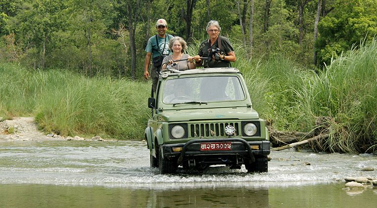 A jeep safari driving through the jungle of Chitwan National Park with tourists viewing wildlife
