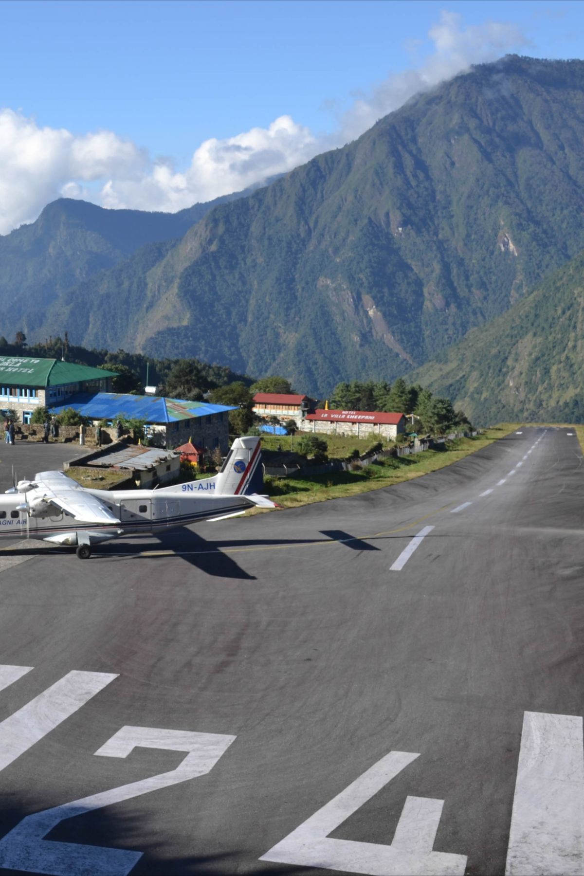 Small plane on the Lukla airport runway with mountains in the background