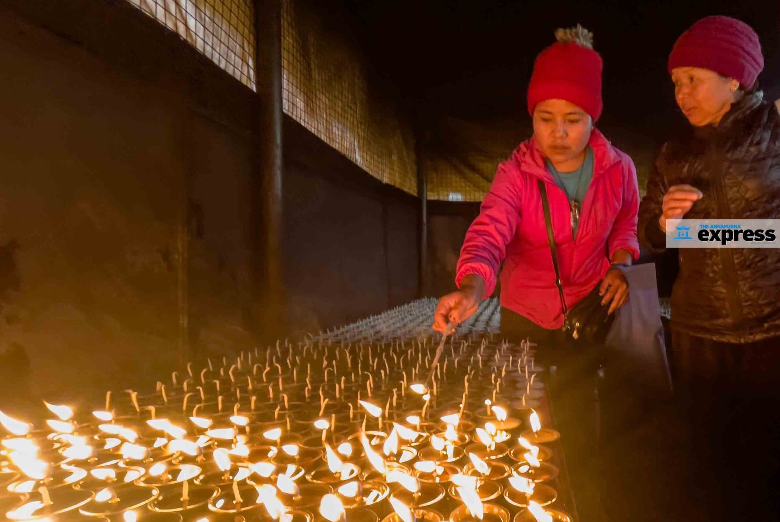 A devotee lighting oil lamps at a Pokhara temple