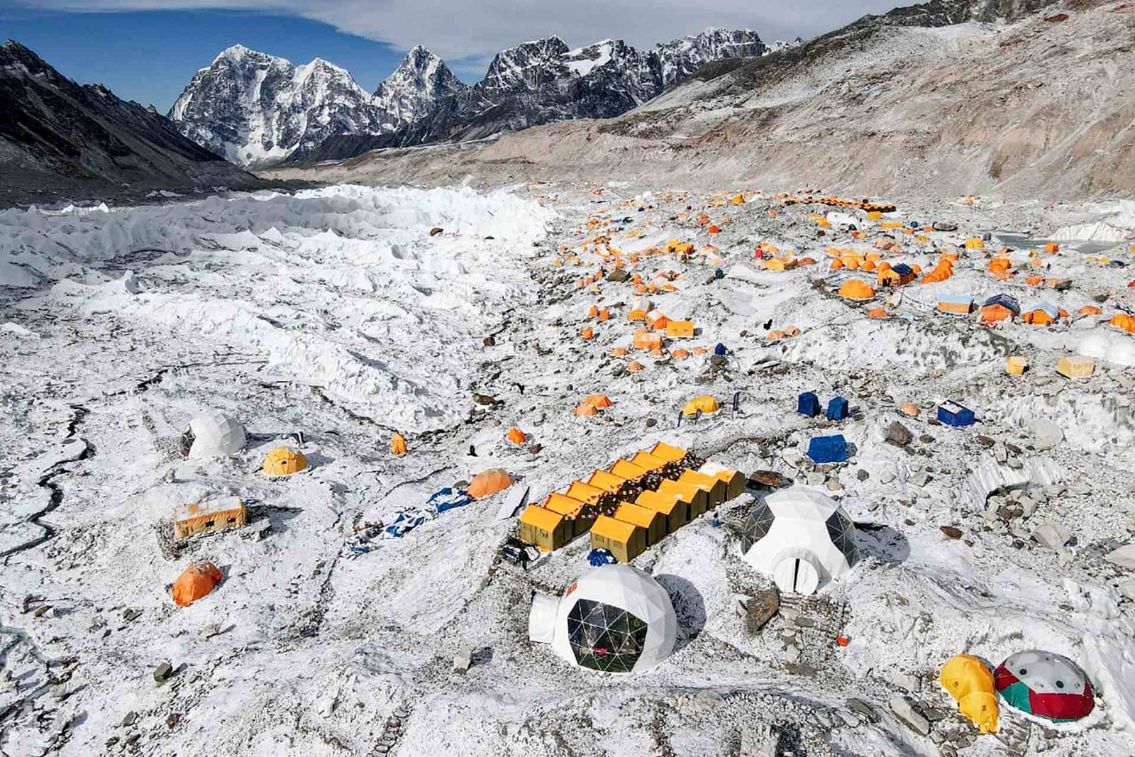 A hand holding an insurance card and passport at a high-altitude base camp.