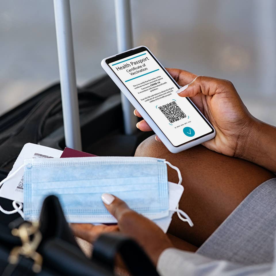 Traveler holding passport and vaccine certificate at an airport checkpoint.