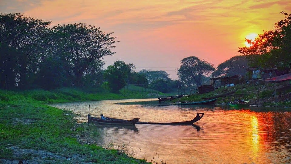 A view of the Rapti River in Sauraha with traditional boats and lodges in the background